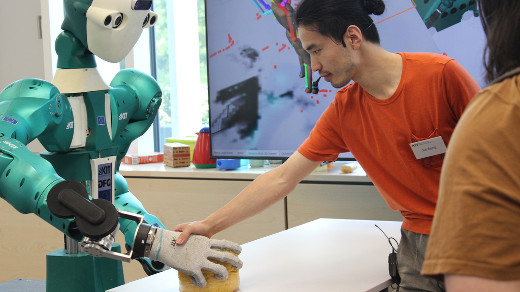 Ein Mitarbeiter arbeitet mit dem humanoiden Roboter ARMAR-6