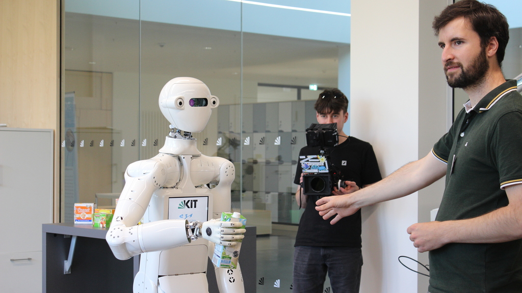 Der humanoide Roboter ARMAR-7 übergibt einem Mann einen Tetrapack Milch